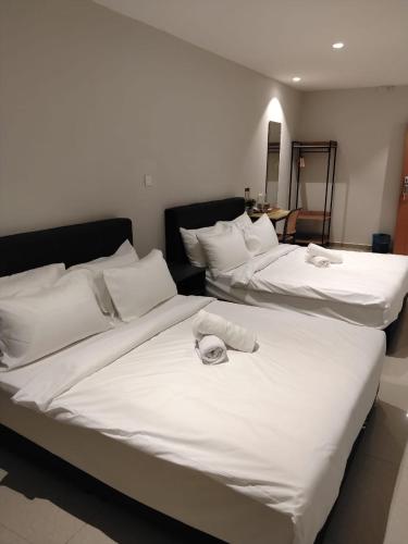 two beds with white sheets and towels on them at Swing & Pillows - Bukit Tinggi, Klang in Klang