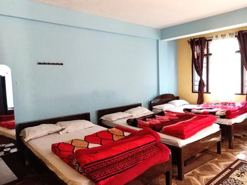 a room with four beds with red blankets on them at Hotel Parichit in Namchi