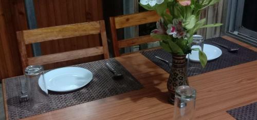 a table with two plates and a vase with flowers at Hotel Parichit in Namchi