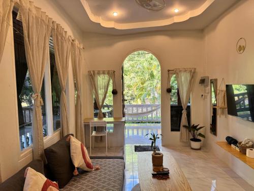a living room with a couch and large windows at My Home Resort - Koh phangan vacation house rentals in Ban Madua Wan