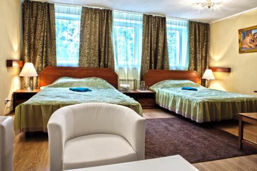 une chambre d'hôtel avec deux lits et une chaise dans l'établissement Roza Vetrov, à Pereslavl-Zalesski