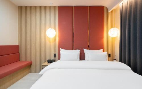 a bedroom with a large bed and a red couch at H Avenue Hotel Gyeryong Eomsa branch in Gyeryong