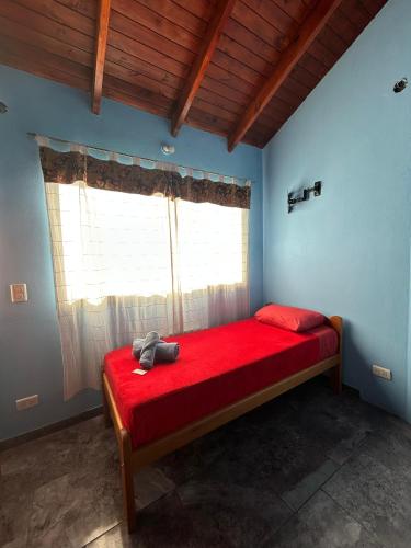 a bedroom with a red bed with a window at Hostel Acuarelas in El Chalten