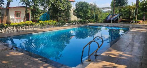 a swimming pool with blue water in a yard at YR'S Nature Farmhouse in Badlapur