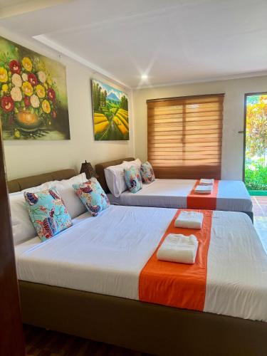 two beds in a room with paintings on the wall at Villa Lourdes Resort in Panglao Island