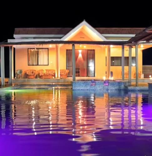 a house with a pool of water in front of it at Aaliya Farm House in Dhauj
