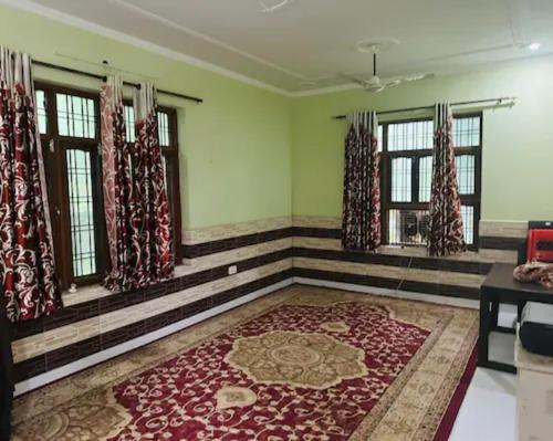 a room with a large rug in a room with windows at Aaliya Farm House in Dhauj