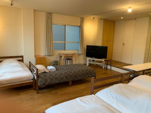 a room with two beds and a flat screen tv at ホテル スミヨシホルモン in Tokyo