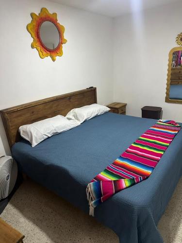 a bed with a blue comforter and a mirror at Cozy house near downtown in Orizaba