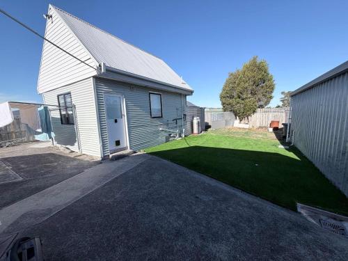 a small white house with a yard of grass at Claremont Comfort Cottage in Claremont