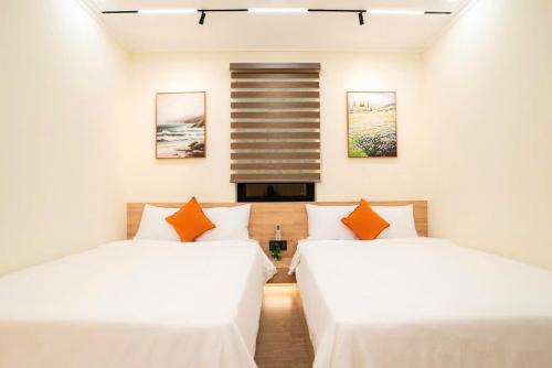 two beds in a room with white walls and orange pillows at Hotel & Apartment Cong Phung in Ấp Bình Hưng