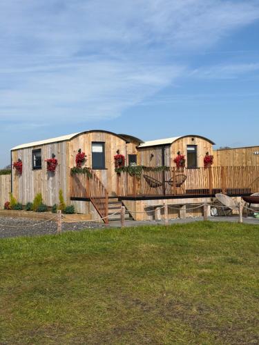 a row of wooden buildings with flowers on them at The Shepherds Chalet in Garstang