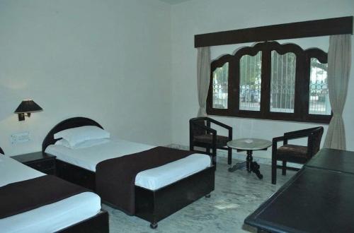 a bedroom with two beds and a table and chairs at Hotel Marble Palace in Khajurāho