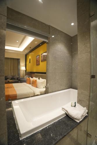 a bathroom with a bath tub and a bedroom at The Murti Hotel and Banquet in Noida