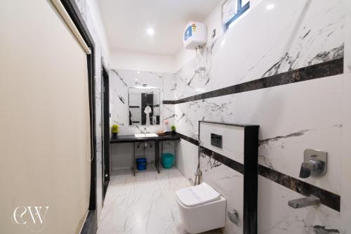 a white bathroom with a toilet and a sink at Rath Inns Beach Resort Mandarmani in Mandarmoni