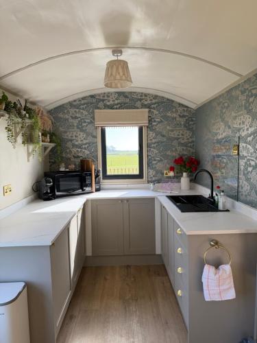 a small kitchen with white cabinets and a window at The Shepherds Chalet in Garstang