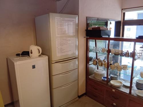 a kitchen with a refrigerator and a shelf with dishes at HOTEL Saboten Apartment in Miyoshi