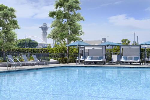 a pool with chairs and umbrellas at Hyatt Regency Los Angeles International Airport in Los Angeles
