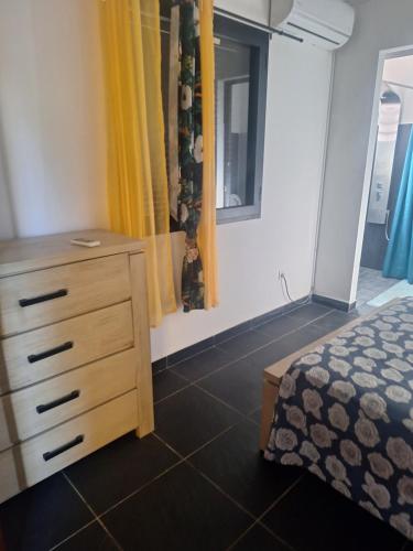 a bedroom with a bed and a dresser and a window at L' ecrin de douceur in Saint-Benoît
