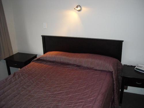 1 dormitorio con 1 cama, 2 mesas y 1 lámpara en St Johns court motel, en Milton