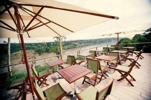 a deck with tables and chairs and umbrellas at Hotel Guaminí Misión in Puerto Iguazú