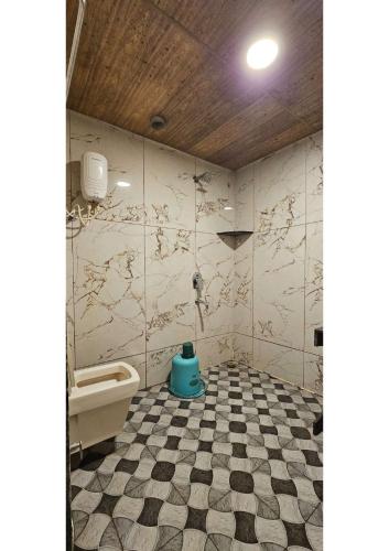a bathroom with a toilet and a checkered floor at Netrani Residency in Māvalli