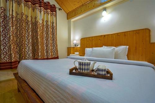 a bedroom with a bed with a tray with two candles at Pine Wood Chalet in Manāli