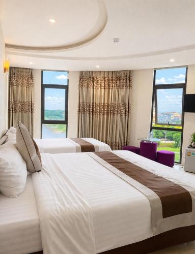 a bedroom with two large beds and large windows at White Rose Hotel in Dong Hoi