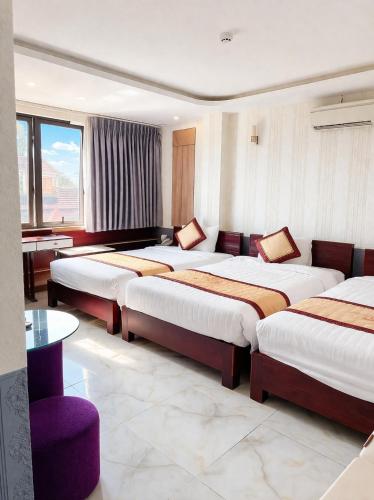 a hotel room with three beds and a couch at White Rose Hotel in Dong Hoi