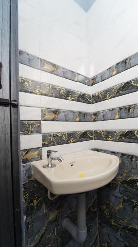 a white sink in a bathroom with tiled walls at MM Hotel Grey Luxury in Coimbatore