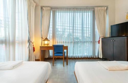a hotel room with two beds and a desk and a window at Collection O Dinso Home Boutique in Bangkok