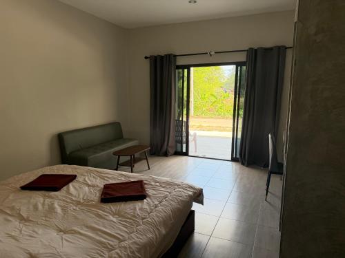 a bedroom with a bed and a couch and a sliding glass door at I mee Lanta Home in Phra Ae beach