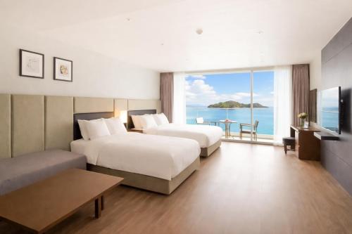 two beds in a hotel room with a view of the ocean at Venezia Hotel and Suite in Yeosu
