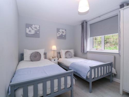 two beds in a bedroom with a window at Sunny Cottage in Brecon