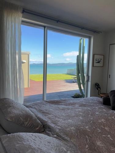 a bedroom with a large window with a view of a cactus at Raumati Sunsets in Raumati Beach