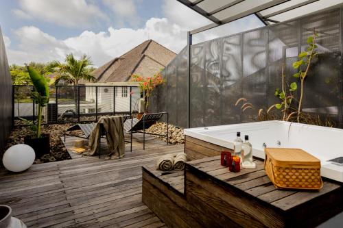 a bathroom with a tub on a wooden deck at The Lima Ocean Suites Pererenan in Canggu