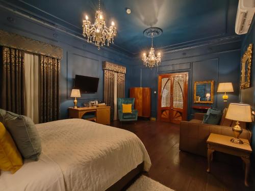 a bedroom with blue walls and a bed and chandeliers at Julina Boutique Living in Mosta