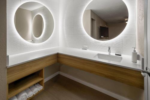 a bathroom with a sink and two mirrors at Super 8 by Wyndham Ellenton Bradenton Area in Ellenton