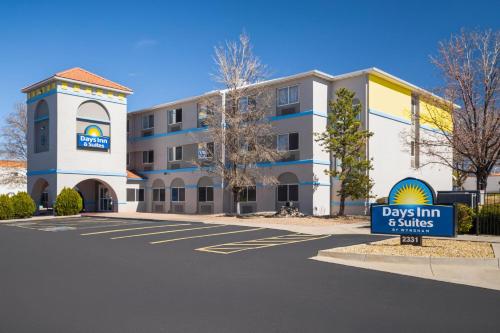 a building with a sign in a parking lot at Days Inn & Suites by Wyndham Airport Albuquerque in Albuquerque