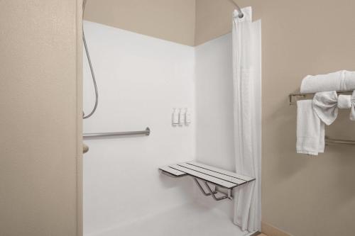 a white bathroom with a shower and a mirror at Days Inn & Suites by Wyndham Airport Albuquerque in Albuquerque