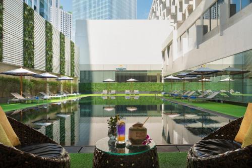 a pool in the middle of a building with chairs and umbrellas at Mandarin Hotel Managed by Centre Point in Bangkok