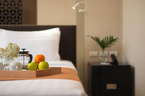 a tray of fruit on a bed in a hotel room at Mandarin Hotel Managed by Centre Point in Bangkok