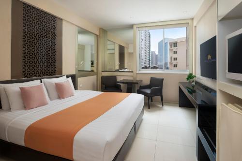 a hotel room with a large bed and a television at Mandarin Hotel Managed by Centre Point in Bangkok