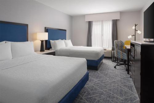 a hotel room with two beds and a desk at Hampton Inn Augusta Fort Eisenhower in Augusta