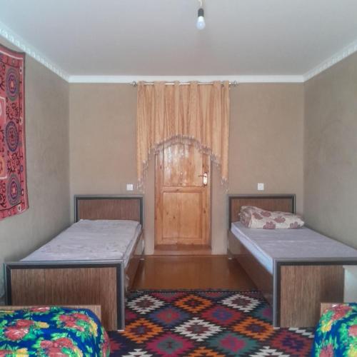 two beds in a room with a door at Le Fortin in Samarkand