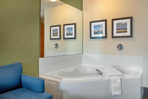 a bathroom with a tub and a chair and a mirror at Comfort Inn & Suites Salem Northeast in Salem