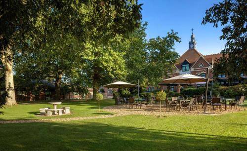 a park with tables and umbrellas in front of a building at DoubleTree by Hilton Stratford-upon-Avon, United Kingdom in Stratford-upon-Avon