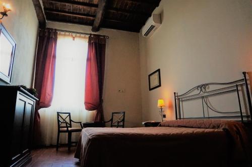 a bedroom with a bed and a window with red curtains at Agriturismo Antico Borgo Poggitazzi in Loro Ciuffenna