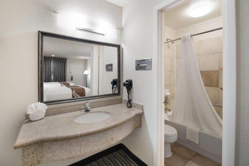 a bathroom with a sink and a toilet and a mirror at Quality Inn & Suites Lufkin in Lufkin