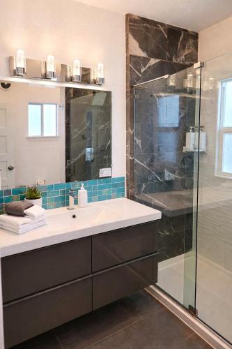a bathroom with a sink and a glass shower at CasaViva Pacifica - 2BR Sleeps 10 with Firepit, BBQ & Shared Yard - Walk to Hillcrest Fun, Near Zoo, Balboa Park & Beaches in San Diego
